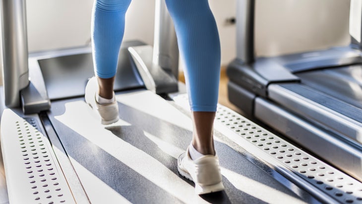 Close-Up view of woman's legs on a treadmill while exercising in a gym.