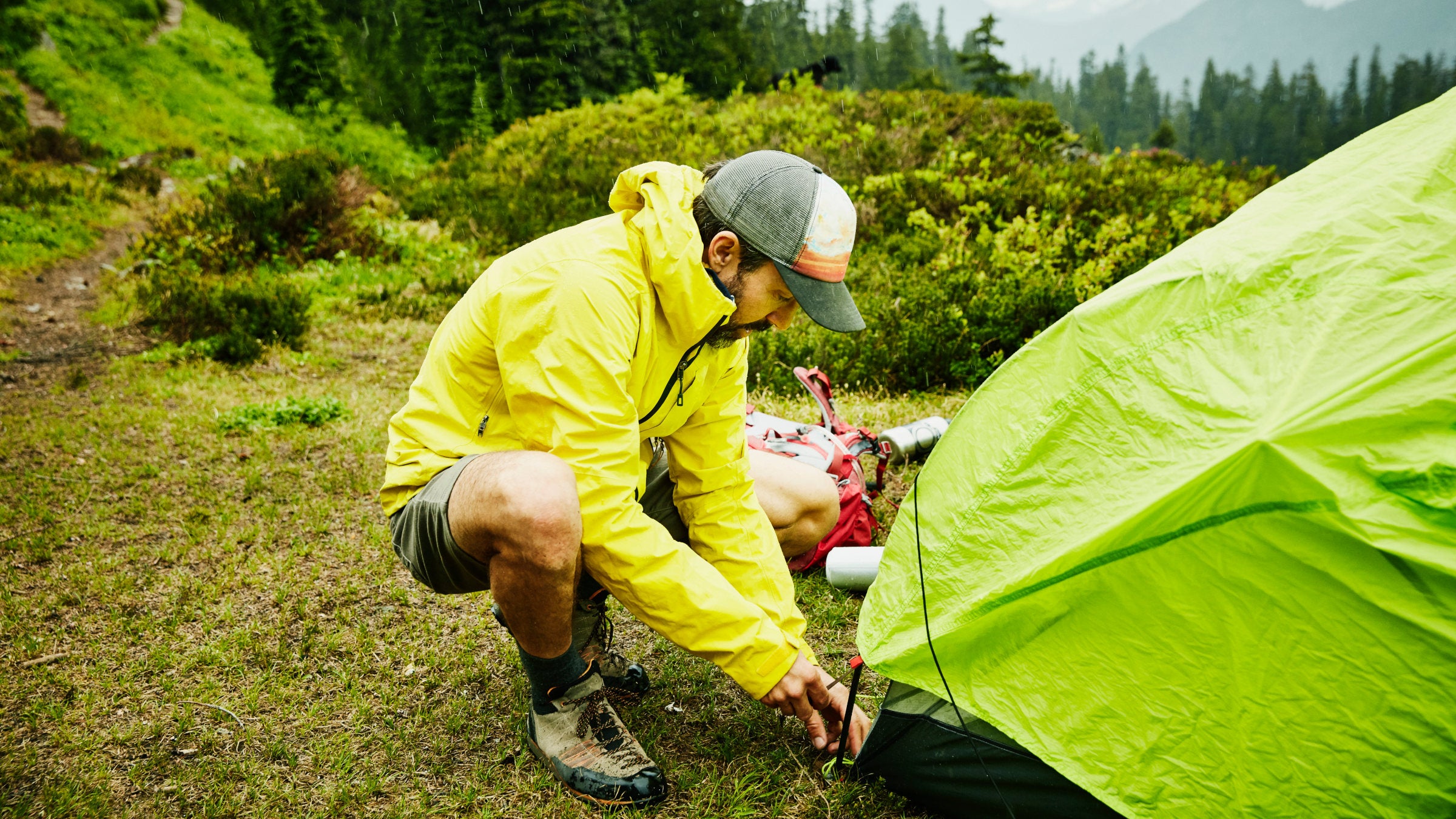 A camper adjusts the rainfly on his tent