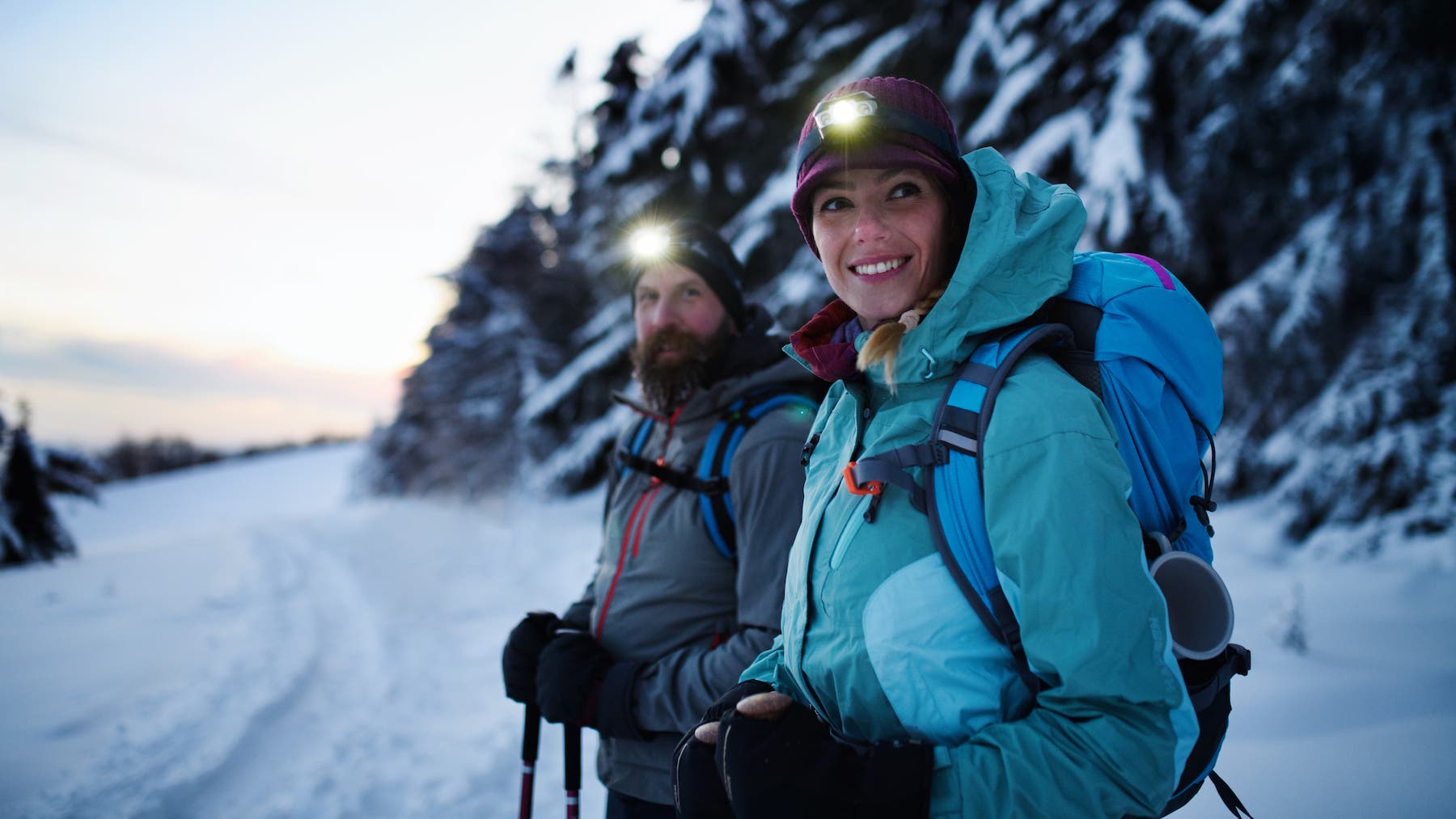 Man and woman walking on mountain ridge wearing many layers.
