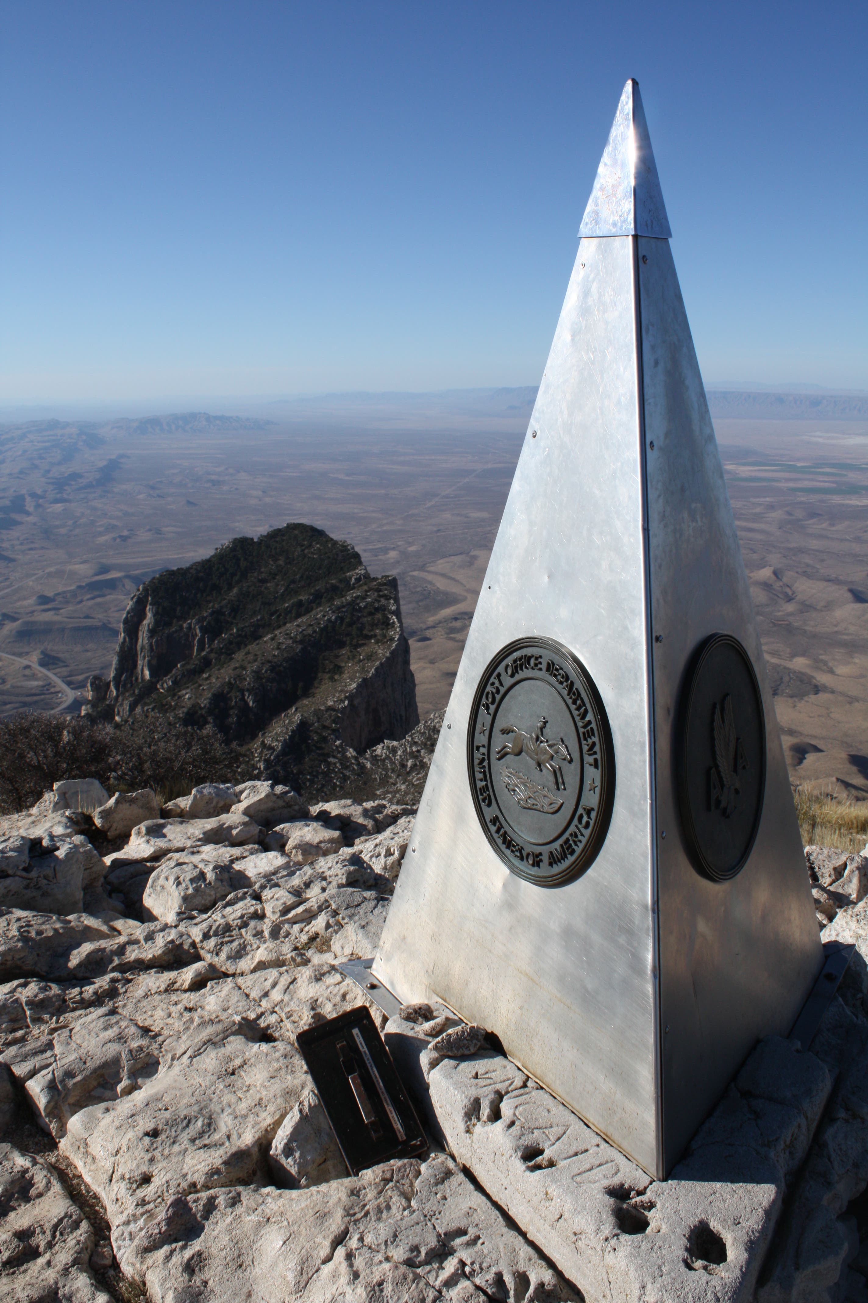 The American Airlines Monument on the summit of Guadalupe Peak with El Capitan just behind.. A large, silver pyramid denotes the American Airlines Monument at the summit of Guadalupe Peak.