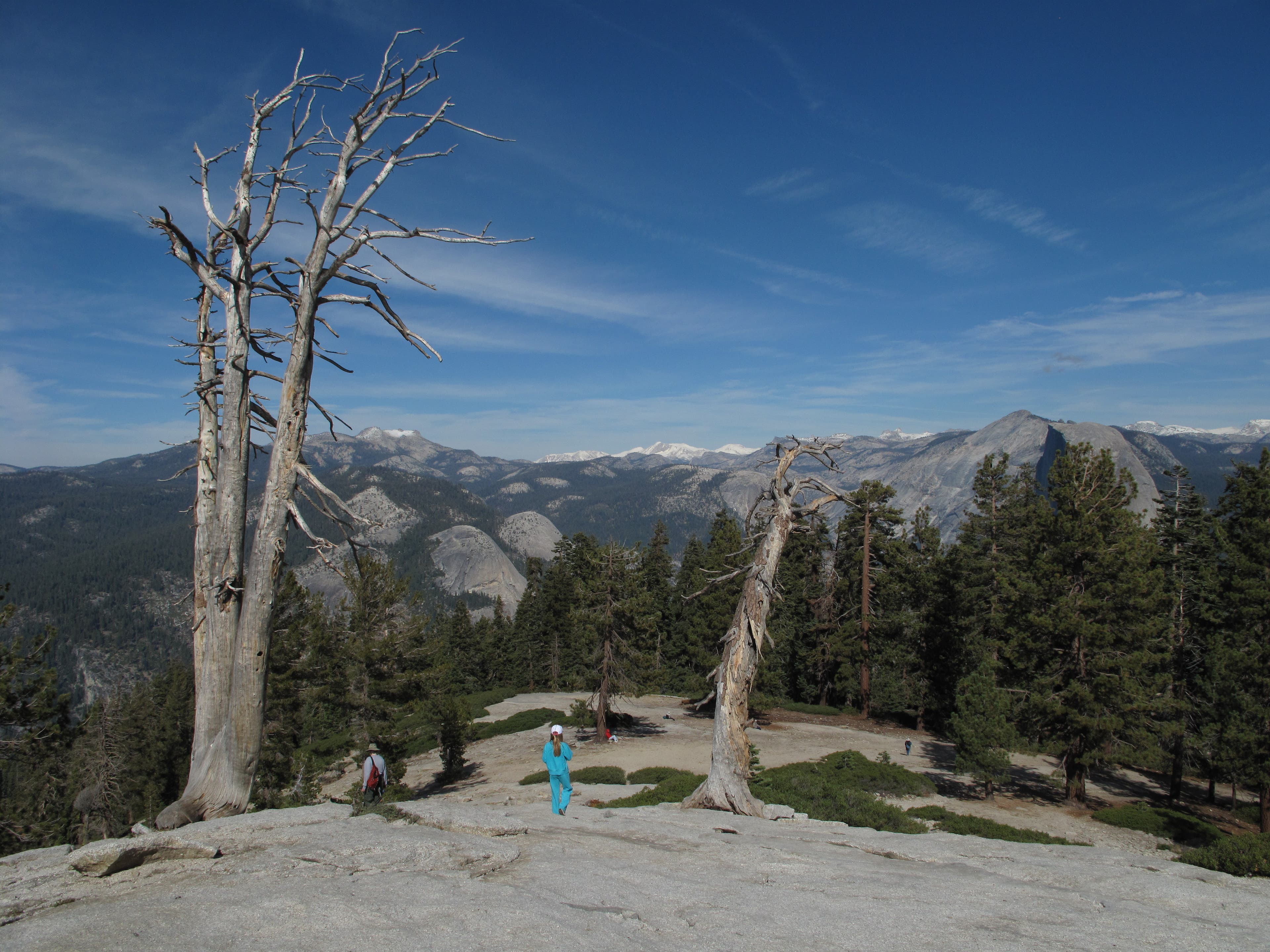 Cathedral Range as seen from Sentinel Peak on the Pohono Trail. A couple hikers traipse across Sentinel Peak with a backdrop of the snow-covered Cathedral Range.