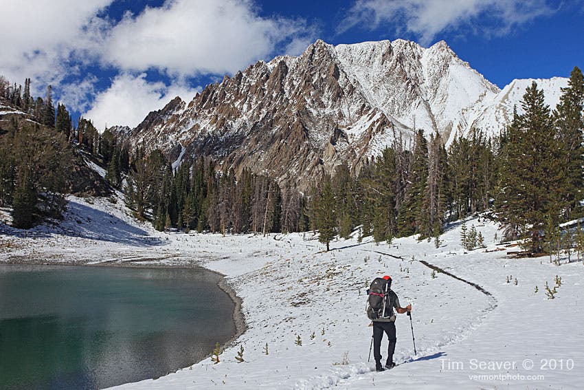 Hiker makes his way along the snow-covered White Cloud Loop Trail through Chamberlain Basin beneath the towering Castle Peak. 