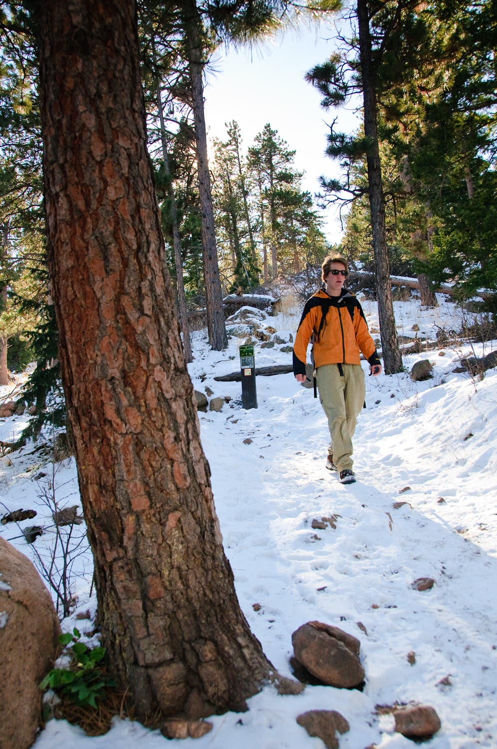 The hike back down the Chautauqua Trail along the Flatirons Loop. Guy in an orange jacket walking along the snow-covered Chautaqua Trail.