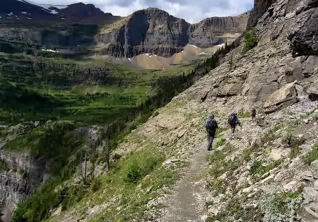 Three people hiking along an exposed trail called the Cliffside Slope. 