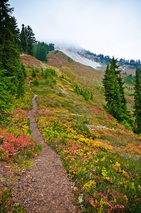 A thin dirt trail heads up to the cloud- and snow-covered Copper Ridge. 