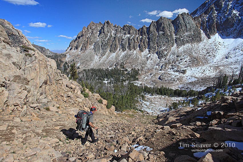 Hiker descends a rocky trail to Quiet Lake where you can camp after day one of hiking the White Cloud Loop Trail. 