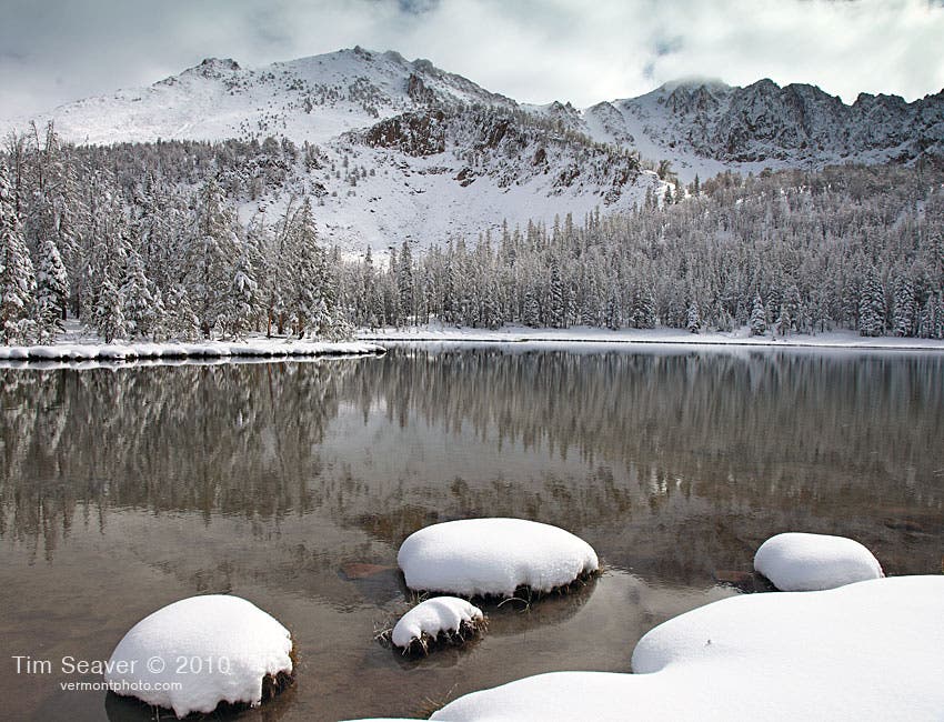 Fourth Of July Lake, White Cloud Loop Trail Hike Surrounded by the snow-covered mountains of the White Cloud Wilderness, Fourth of July Lake is still as glass.
