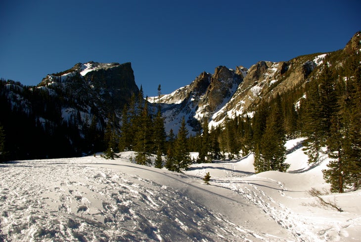 Hallet Peak and Flattop Mountain loom above the snow-covered trail to Emerald Lake. 