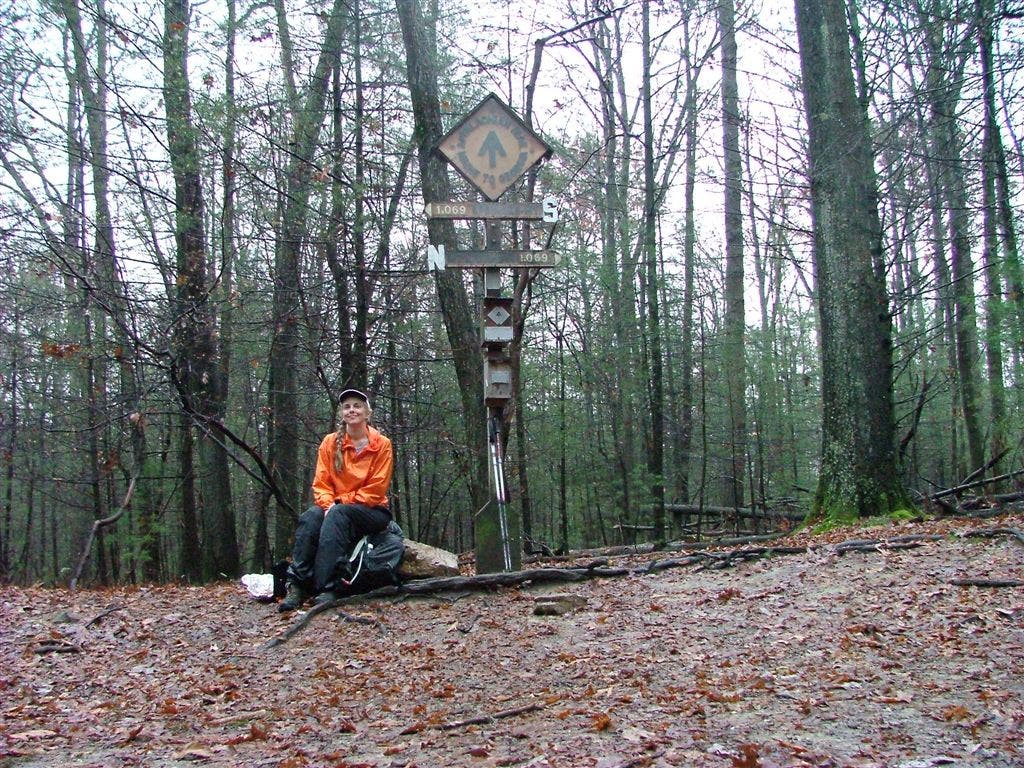 Hiker rests next to AT midpoint sign None