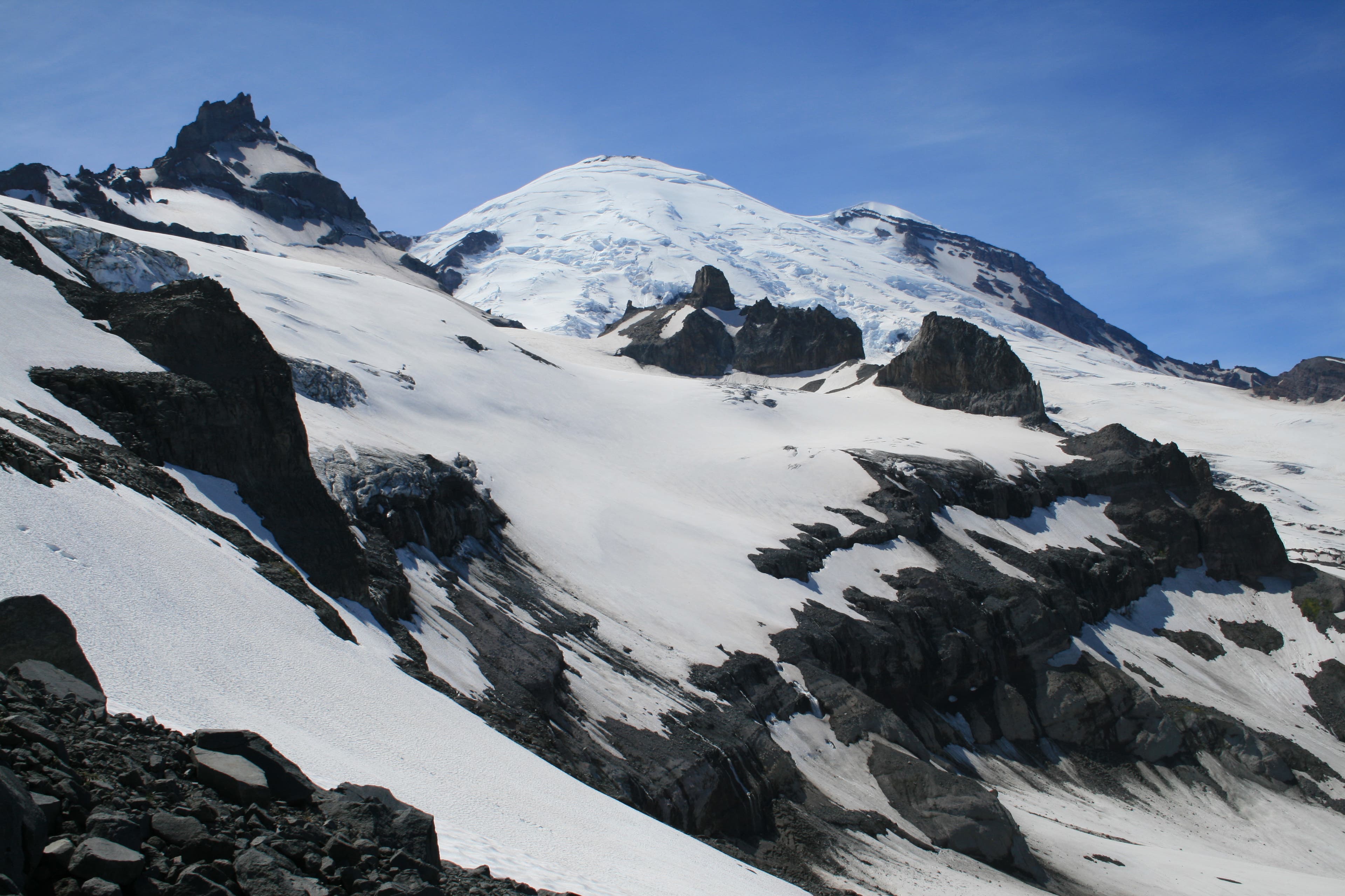 The snow-capped peak of Mount Rainier shows itself to hikers hiking the Wonderland Trail between Fryingpan Creek and Mowich Lake. 