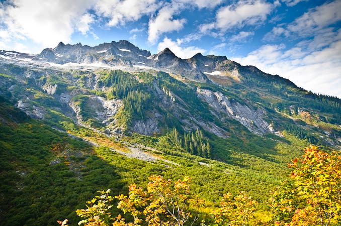 Nooksack Ridge between Hannegan Pass and Beaver Trail. The imposing Nooksack Ridge stands tall beneath a blue sky and over foliage just beginning to change colors for the fall.