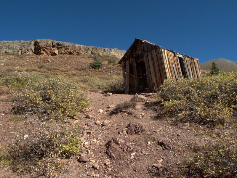 A small wooden mine shaft the looks like a cabin sits along the side of the Colorado Trail not far from the Stony Pass trailhead. 