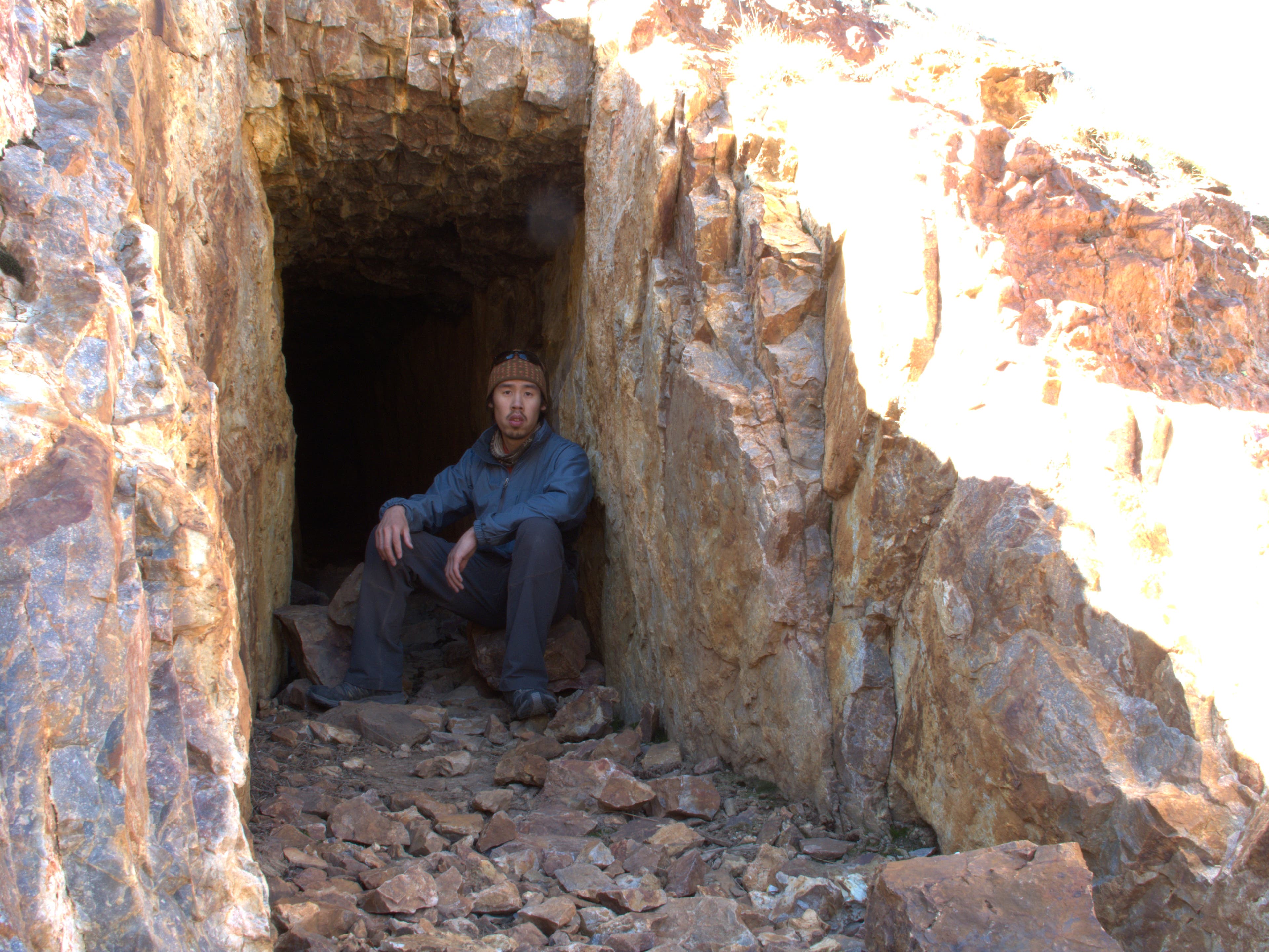 A hiker sits in the shade of an old mine shaft along the Colorado Trail. 