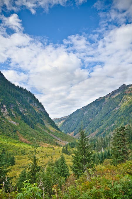 The green mountainsides of Ruth Creek Valley splay their beauty beneath a lightly clouded, bright blue sky. 