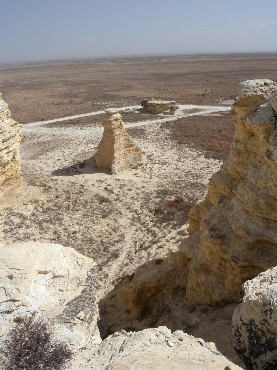 A lone spire in front of a car-park turnaround area.