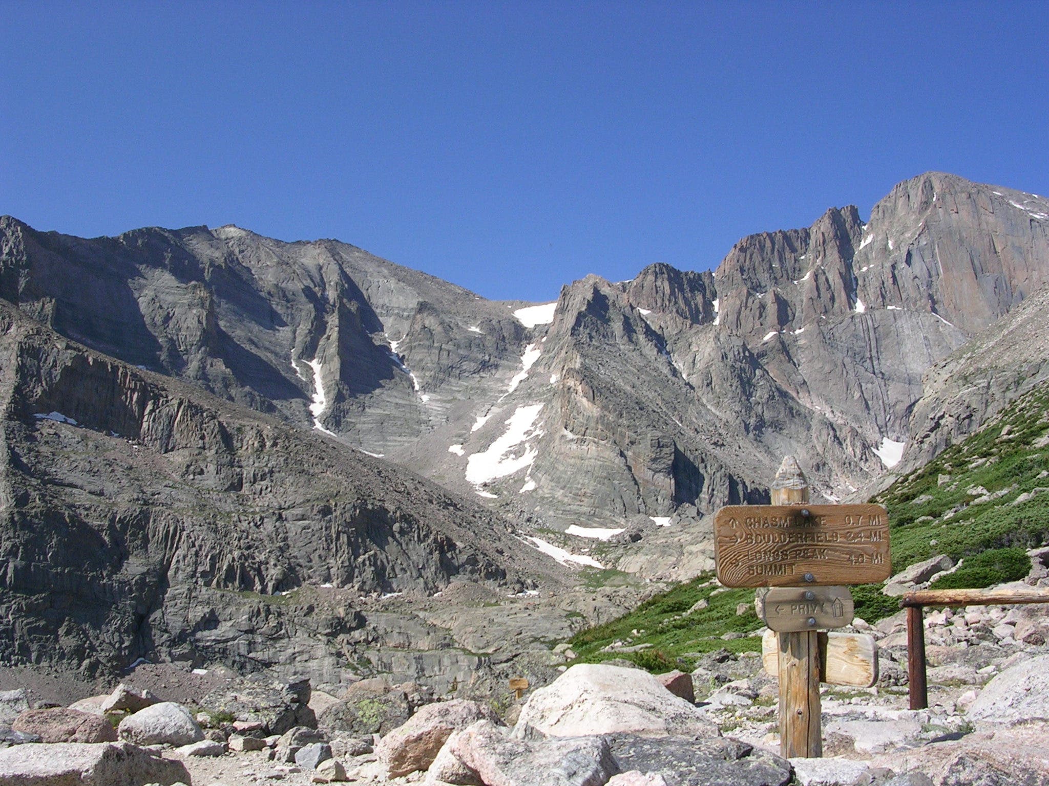 A trail sign details routes to Chasm Lake and Longs Peak summit.