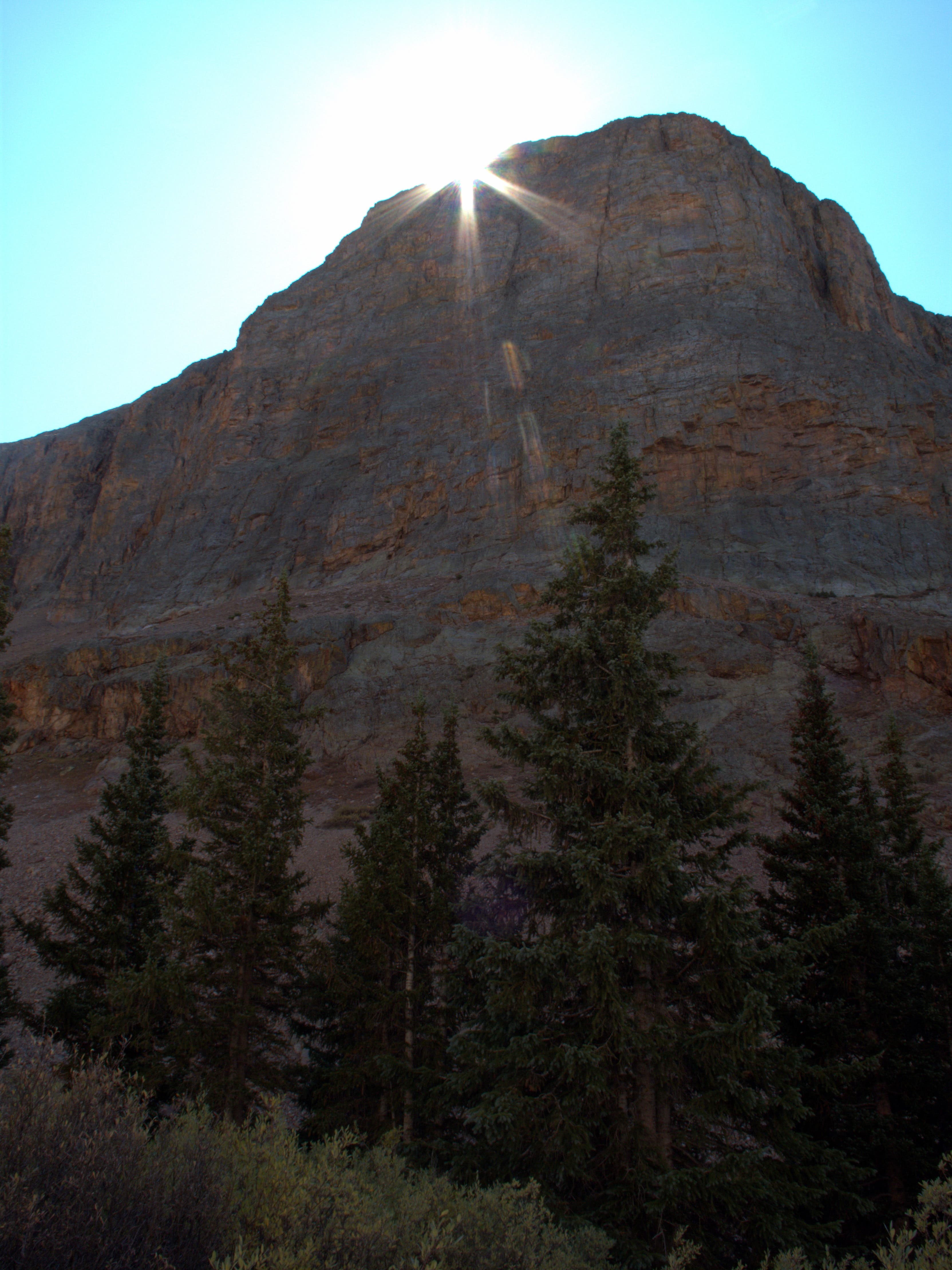 Sun behind vertical rock shelf along the Colorado Trail from Stony Pass to Celebration Lake. Bright sun poking its face over a vertical rock shelf along the Colorado Trail from Stony Pass to Celebration Lake.