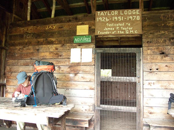 Hiker at a wooden table at Taylor Lodge, one of many shelters along the Long Trail's Section 10 hike. 