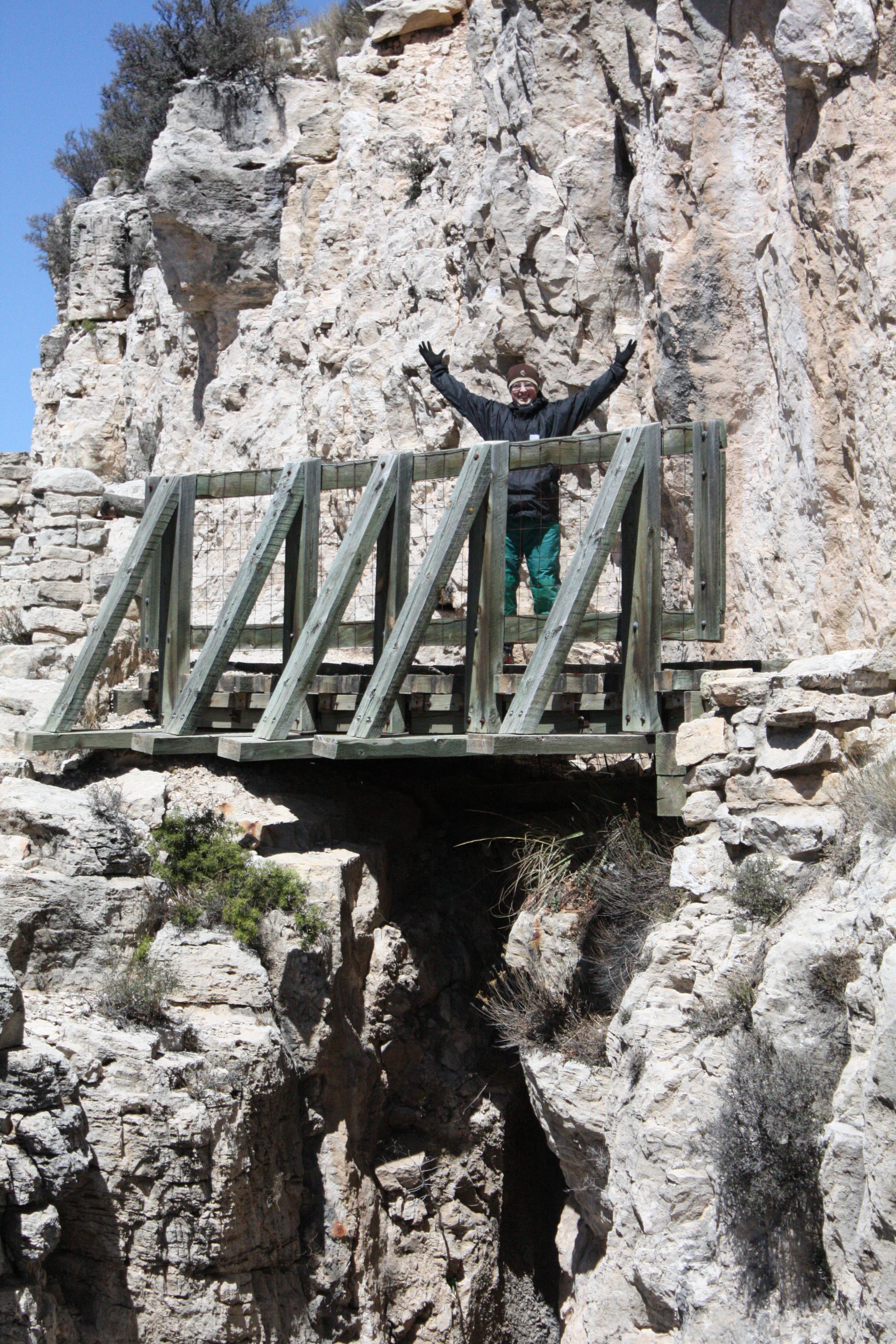 A woman standing on a cliffside, wooden bridge that's the highest bridge in Texas. 