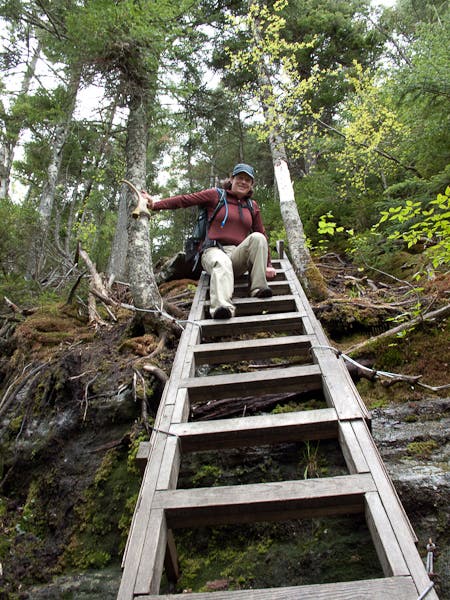 Hiker climbs down a steep trail ladder, one of many necessary to complete section 10 of the Long Trail. 