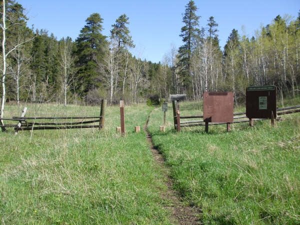 A dirt singletrack and trail signs mark the trailhead for both the Chasm Lake Trail and Long's Peak.