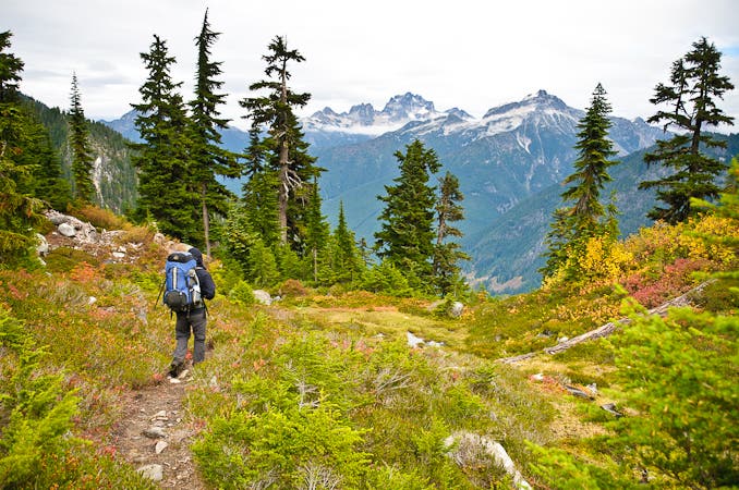 Hiker on a dirt trail looks out over stunning mountain views near Copper Lake. 