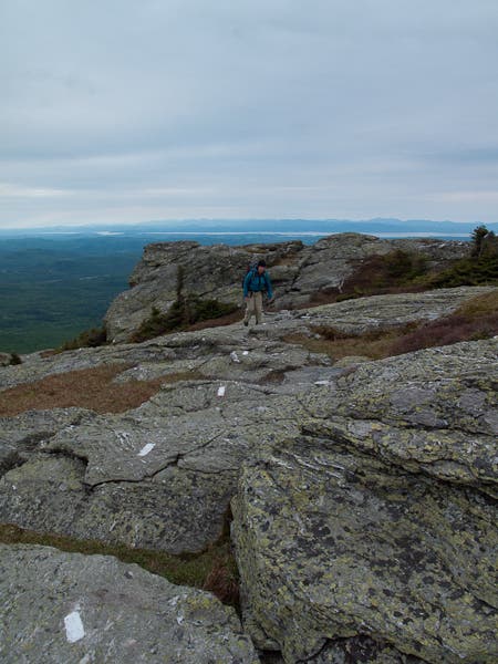 Hiker following the white blazes on the rocks on the summit of Mount Mansfield. 