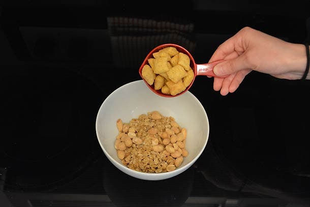 Combine granola, cereal, and honey-roasted peanuts in a bowl.