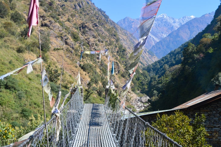 Perilous Crossing Nepal suspension bridges, draped with prayer flags
