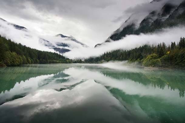 Fog slowly lifts from the forests and mountains surrounding Diablo Lake, an artificial reservoir formed by the damming of the Skagit River at Diablo…