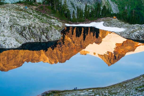 Weekend campers dot the shore of Lake Ann below the imposing massif of Mount Shuksan in Mount Baker-Snoqualmie National Forest. Solitude not…