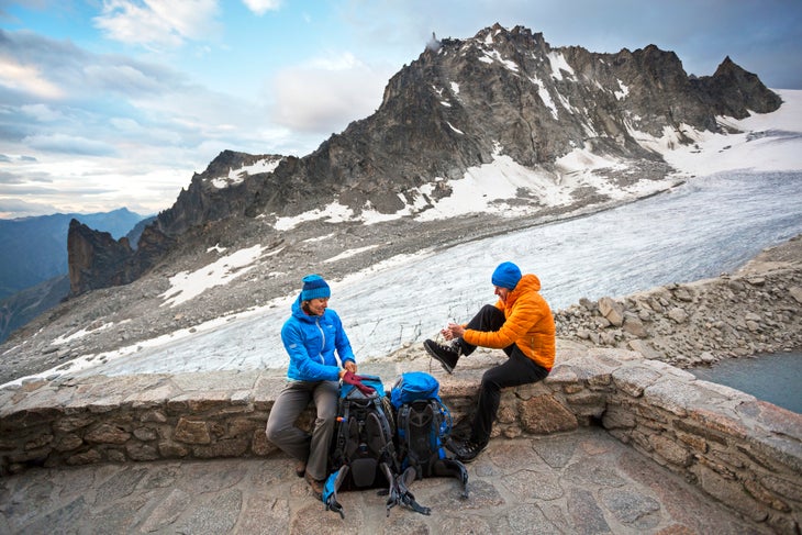 Couple preparing to leave hut Two hikers sitting on the deck of the Cabane d'Orny tying shoes and getting ready to leave for the second day of the Chamonix to Zermatt Glacier…
