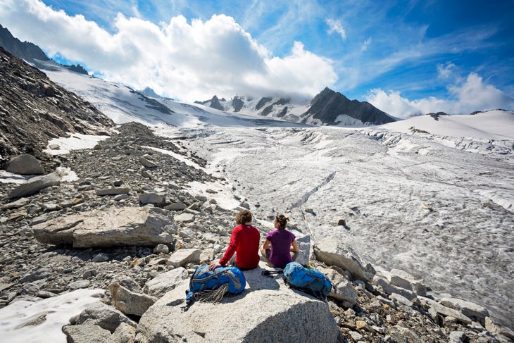 Couple relaxing on edge of glacier Two hikers sitting and taking a break on the edge of the Glacier du Tour on the first day of the Chamonix to Zermatt Glacier Haute Route.