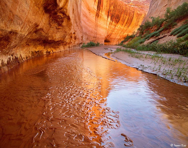 The reservoir first topped off in 1983, with the water surface 90 feet above the streambed of Davis Gulch seen here. The reservoir's white \
