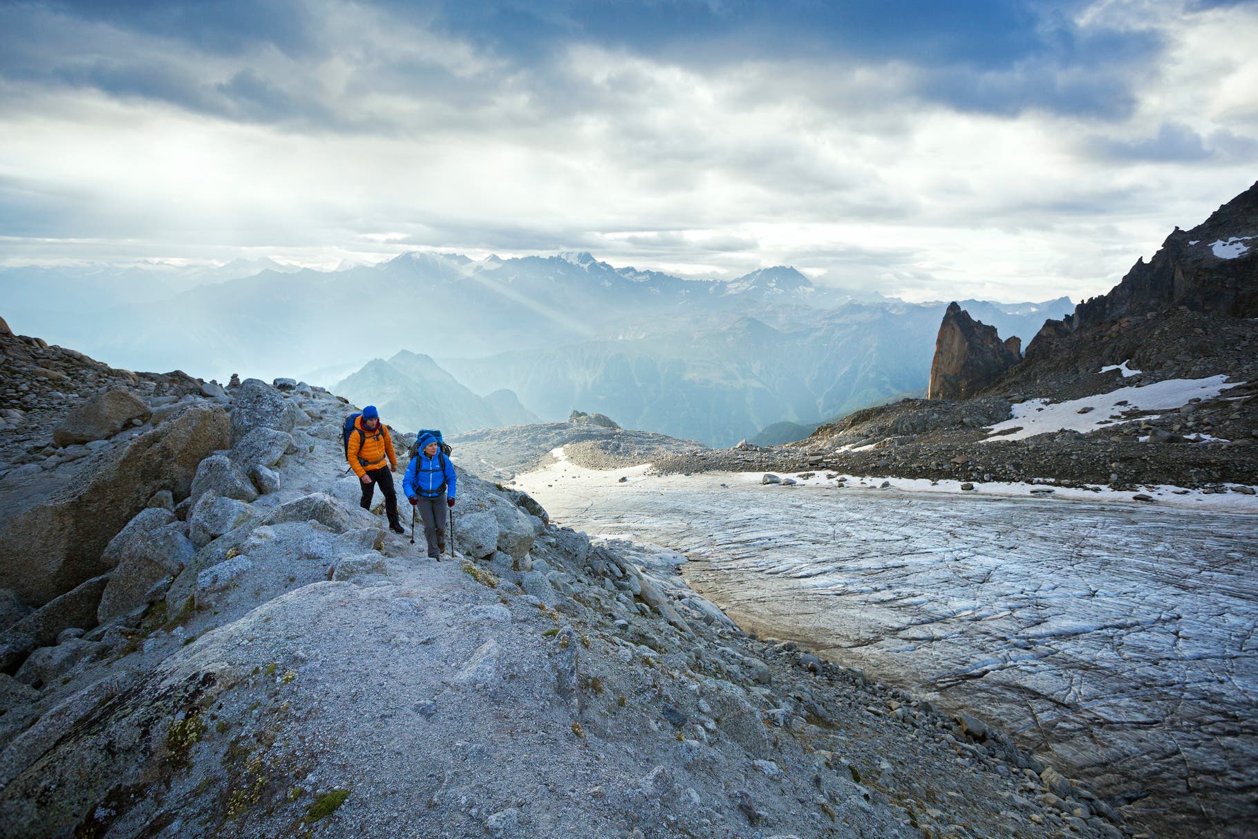 Two hikers walking alongside the Glacier d'Orny on the first day of the Chamonix to Zermatt Glacier Haute Route.