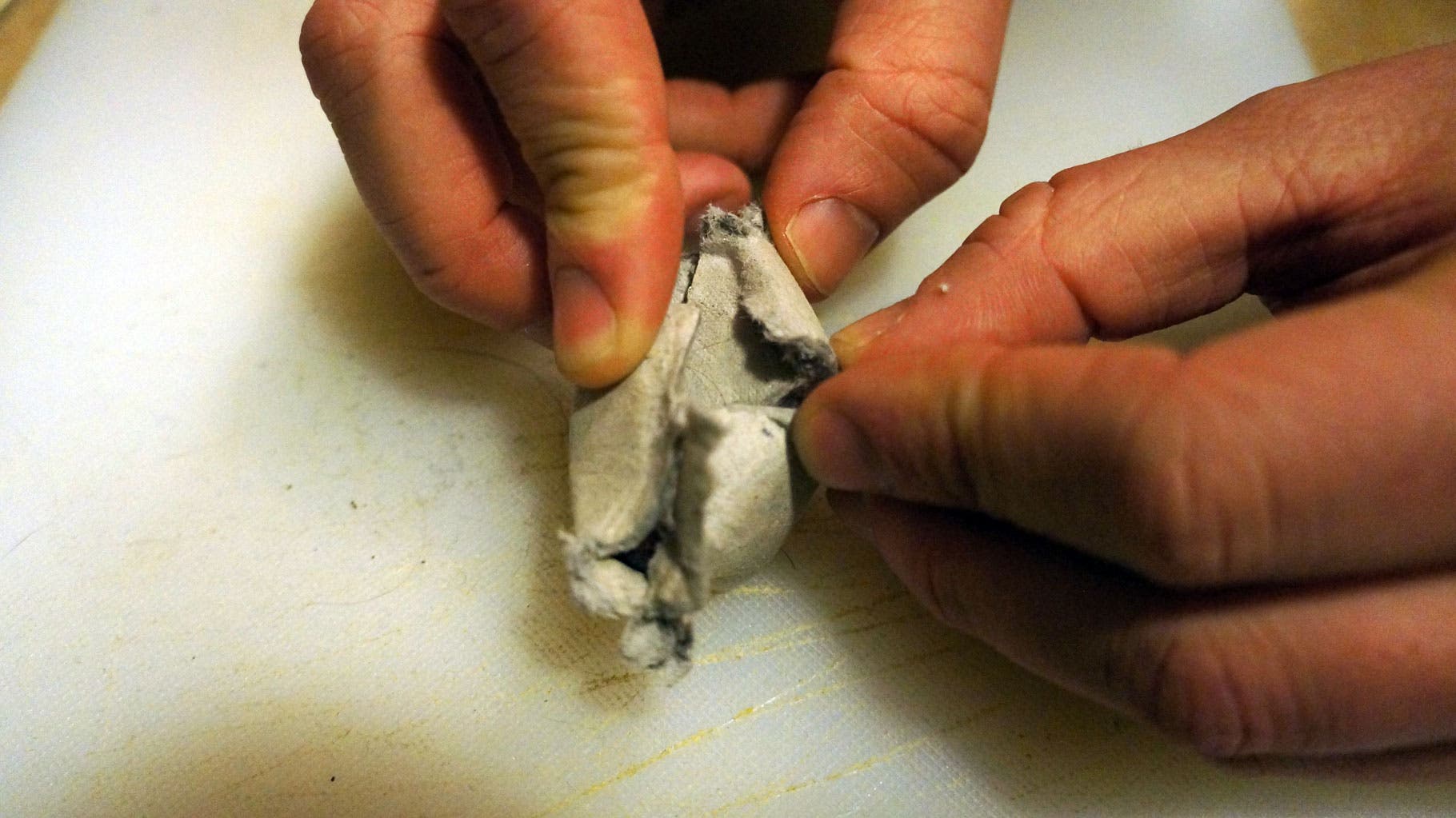 Fold the top edges of the egg crate closed over the dryer lint.