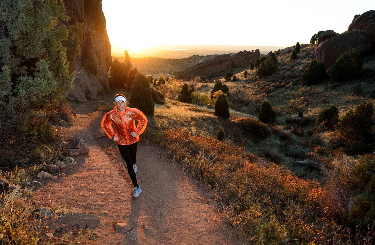 The sun breeches the horizon and the dirt and rocks glow orange on a morning run in Red Rocks Park, Morrison, CO.