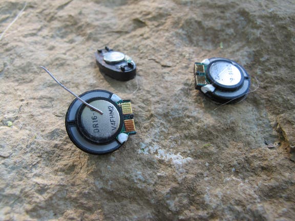 Speakers include tiny magnets inside. Magnetize a small piece of wire by rubbing it in one direction across the magnet