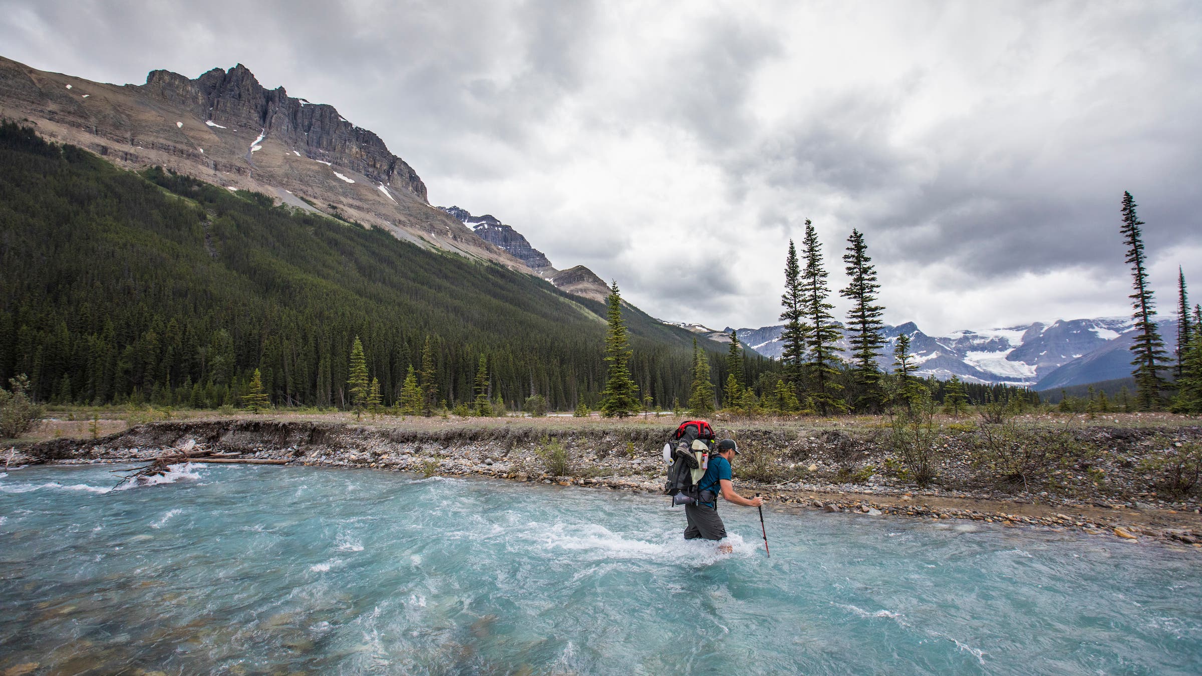 man hikes along a raging river