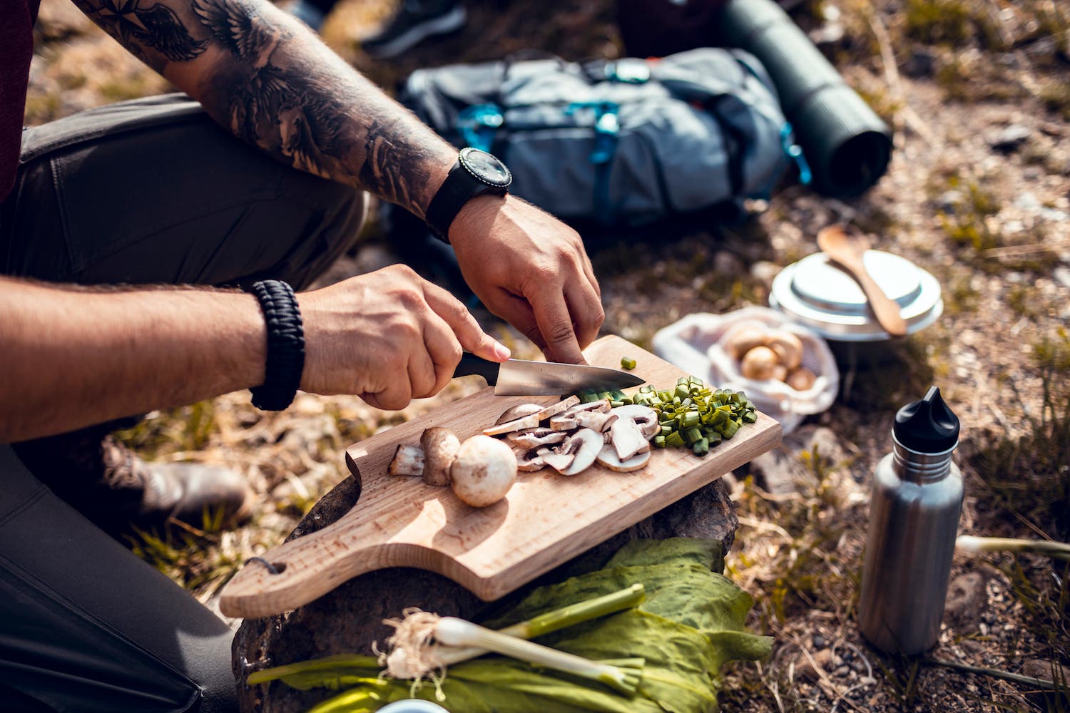 Close up of a young woman chopping up fresh vegetables while taking a break from hiking