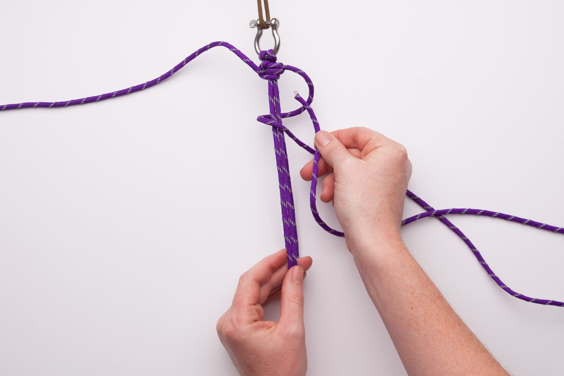 Now go back to the right string. This time wrap it behind the middle cords and around to the front, leaving a small loop. Thread that string though…