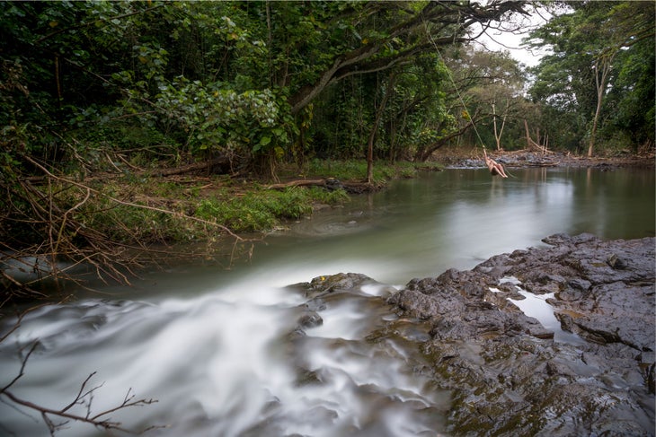 Hiker swings over the pool of water near Hoopii Falls to cool down after one of Kauai's best hikes.