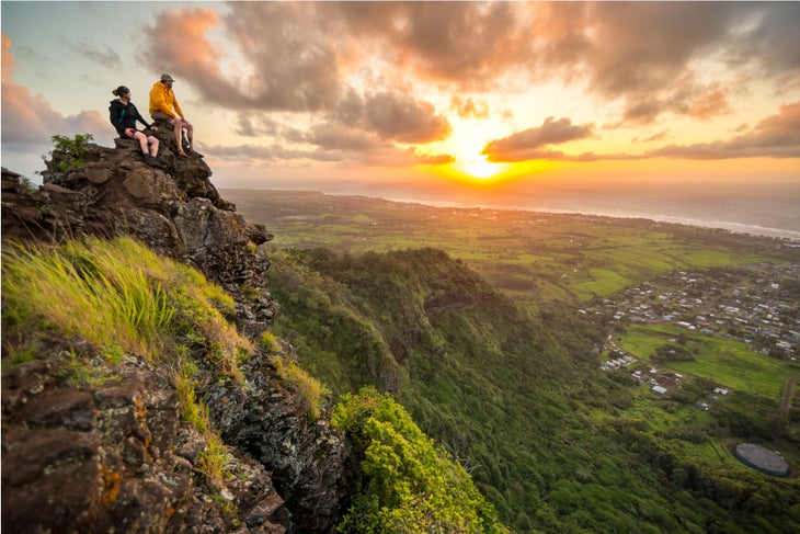 Two hikers sit at the peak of Nounou Mountain, also known as Sleeping Giant, a popular Kaua'i hike. 
