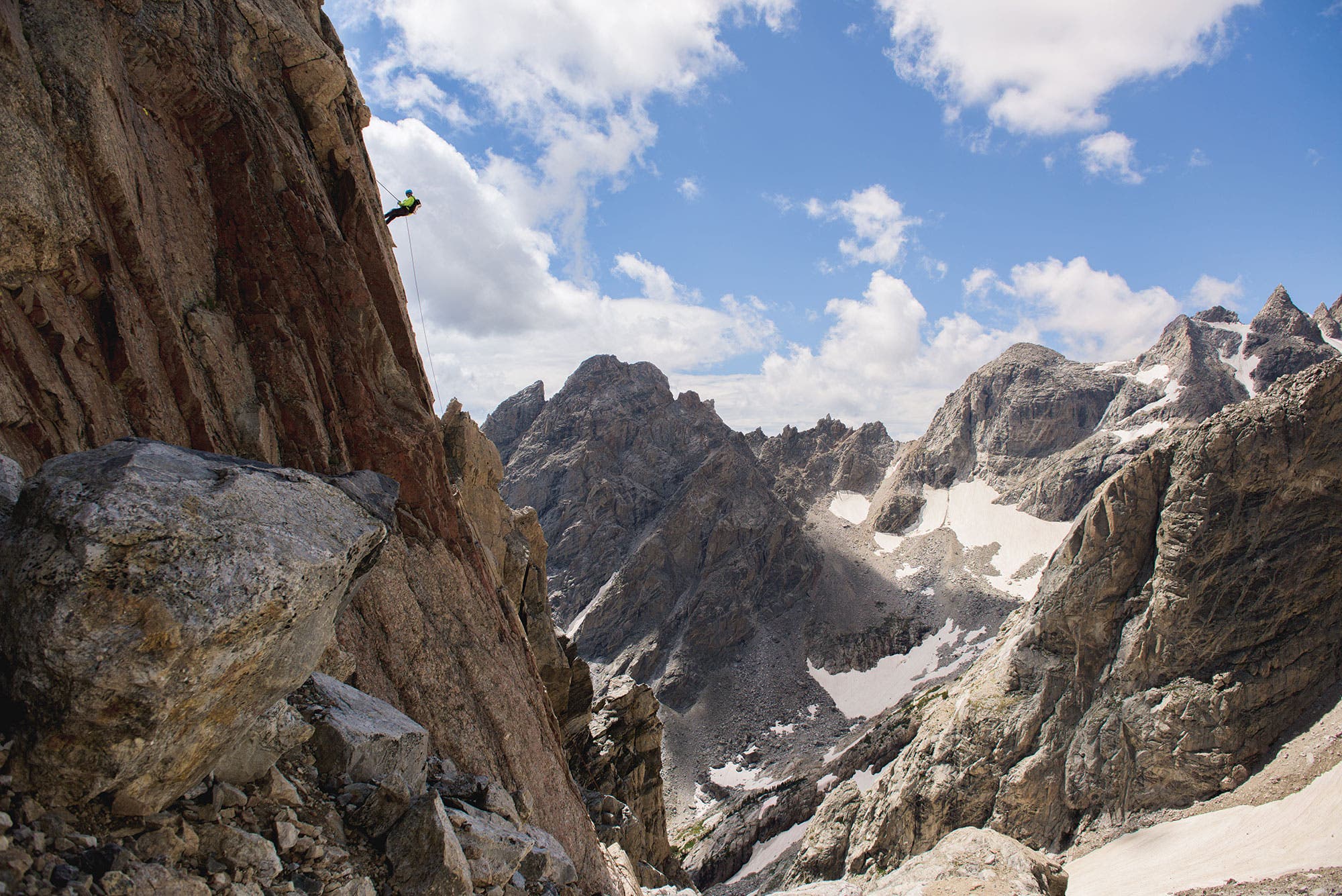 Climber on a Grand Teton rock face surrounded by multiple smaller peaks. 