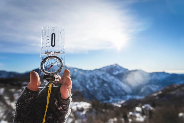 Reading a compass, detail of hand with compass for orientation in the mountains