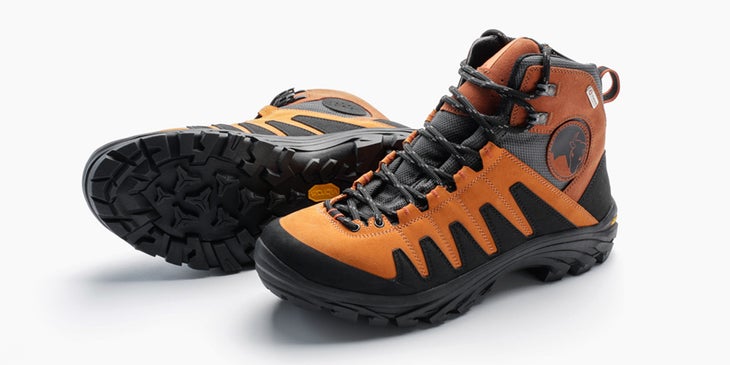 Mishmi_hikingboots_photogallery Orange and black Mishmi hiking boots sit on a white background. One is upright on its sole and the right shoe is lying on its side with the Vibram…