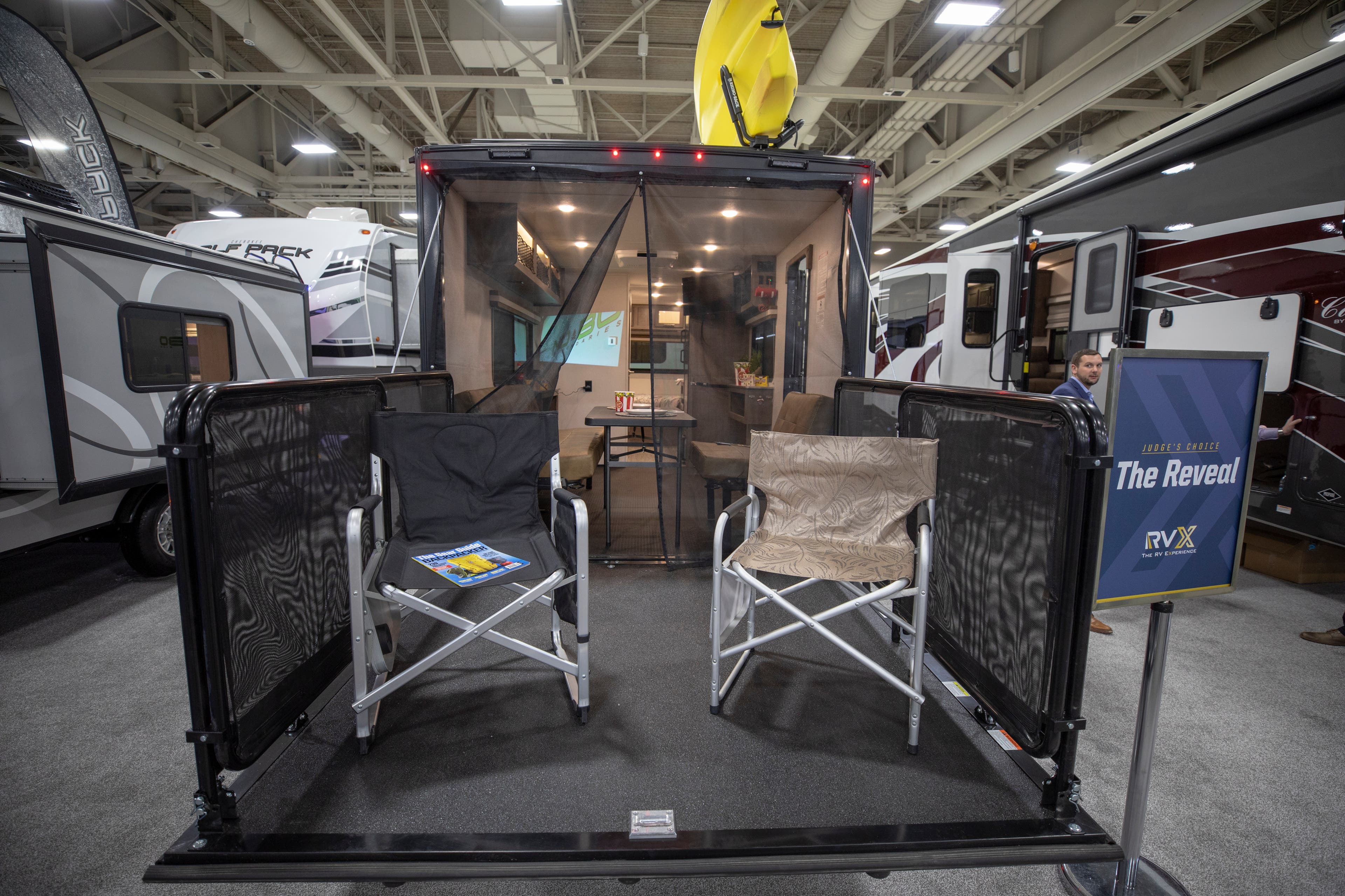 View of the NOBO RV from the deck. Two outdoor chairs sit on the deck behind the RV. A sheer curtain separates the outdoor space from the convertible…