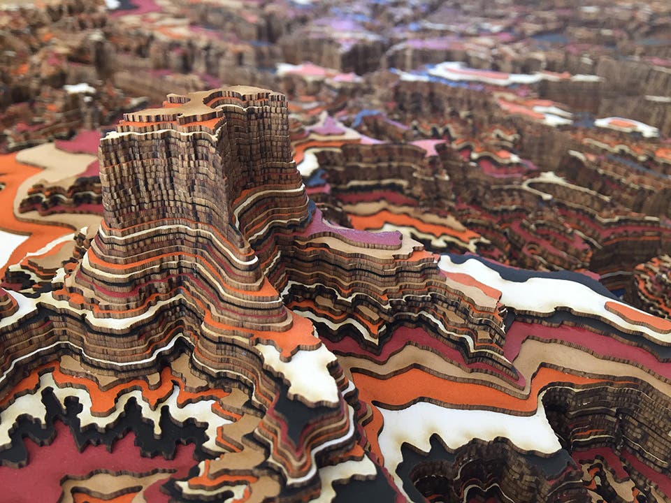 Close up of the layers that comprise a Canyonlands topographic map table. Layers of laser cut cardboard are stacked. Layers are: white, brown,…