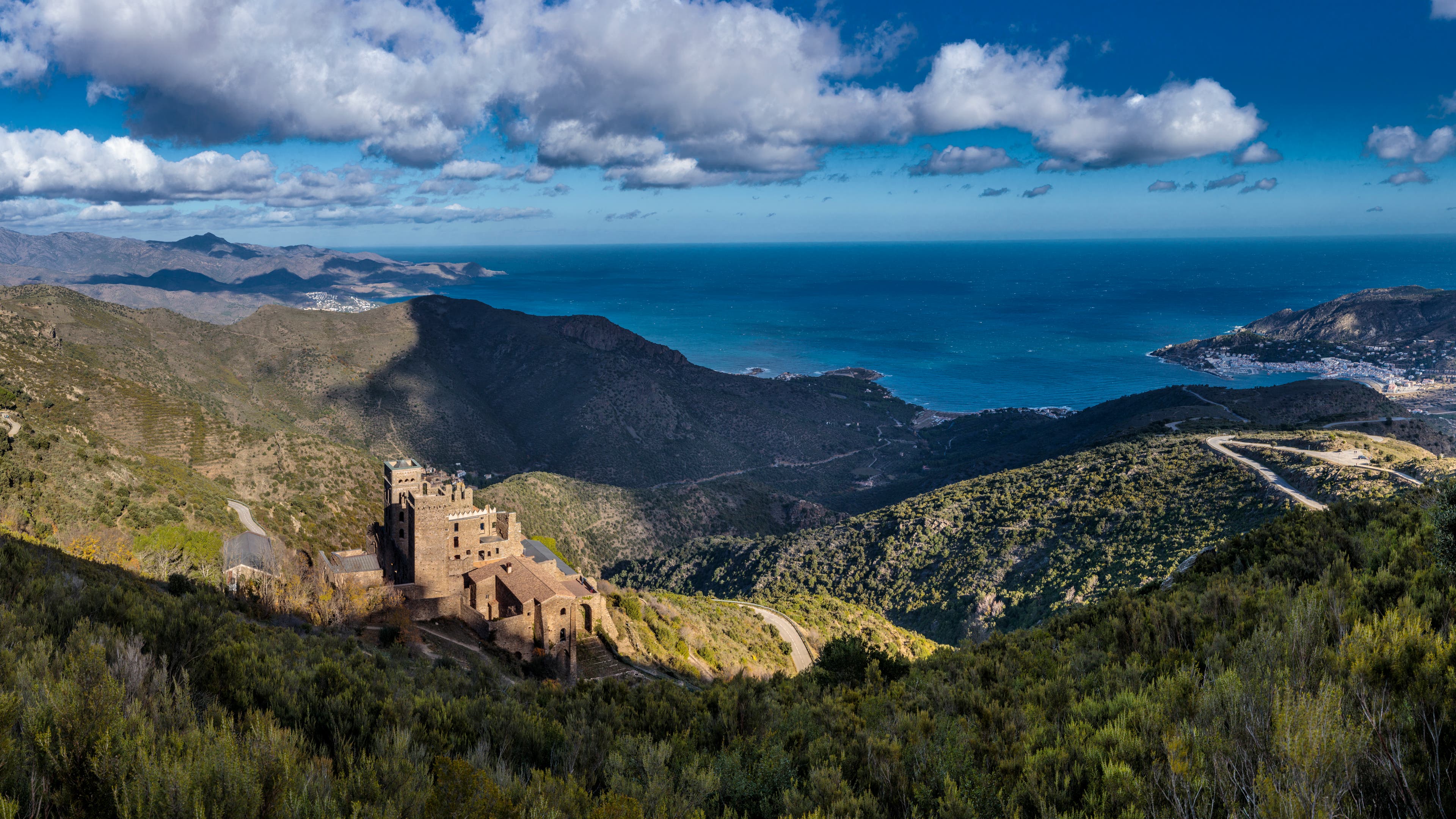 Clouds fill the sky over an ocean view with hills surrounding it. View from Saint James Way in Catalonia, Spain.