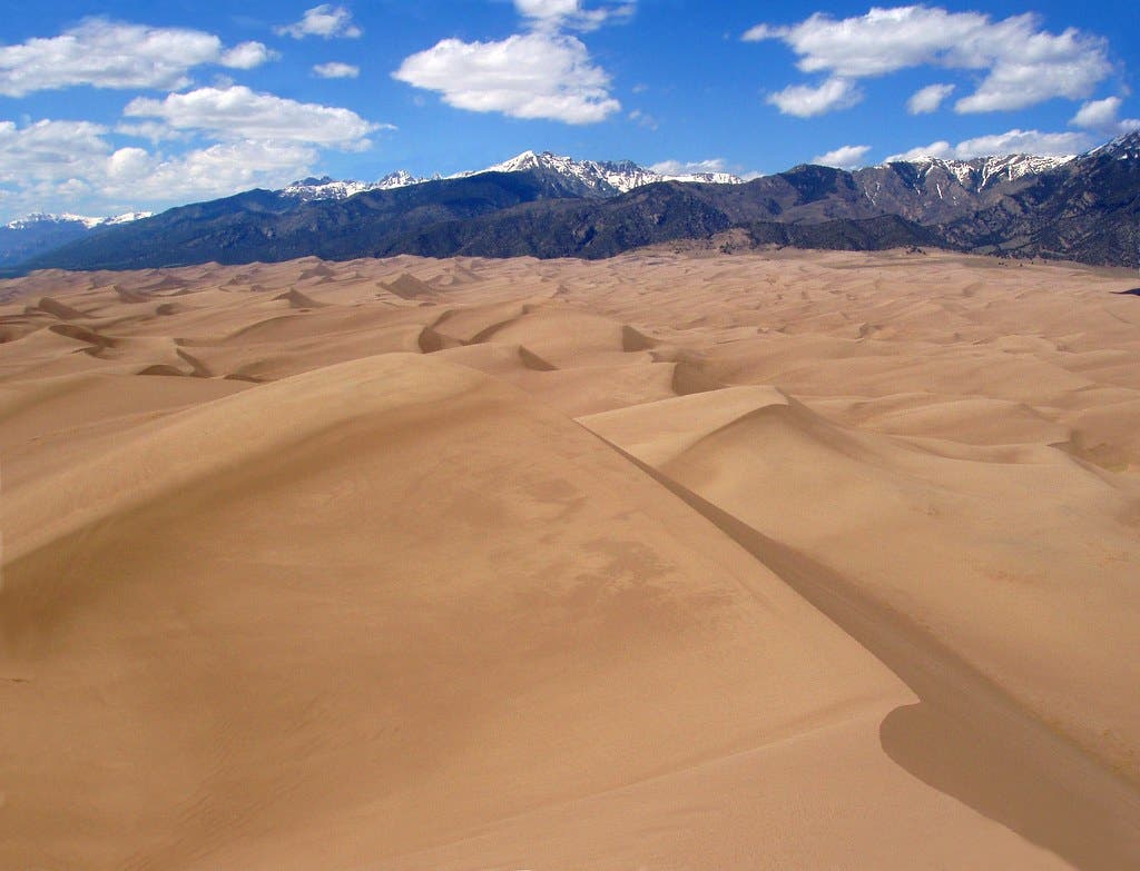 This quintessential desert hike in Great Sand Dunes National Park comprises miles of sand dunes with towering snowcapped mountains as a distant view.